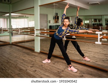 Portrait of young beautiful black woman in choreography hall. Fitness trainer shows a warm-up exercise.