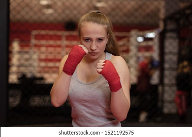  Portrait of young beautiful boxer woman ready to kick with red boxing bandage on hands in gym. Strong hand and fist, ready for fight and active exercise. attention to the red stripes
 - Powered by Shutterstock