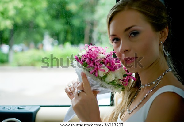 Portrait of young beautiful bride with flowers in\
car. Shallow DOF