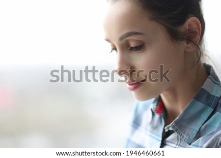 Portrait of young beautiful brunette woman with downcast eyes