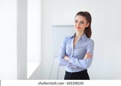 Portrait of young beautiful business woman in the office. Crossed arms