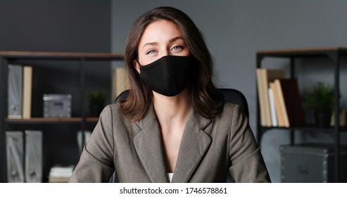 Portrait Of Young Beautiful Businesswoman In Black Mask Sitting In Office.