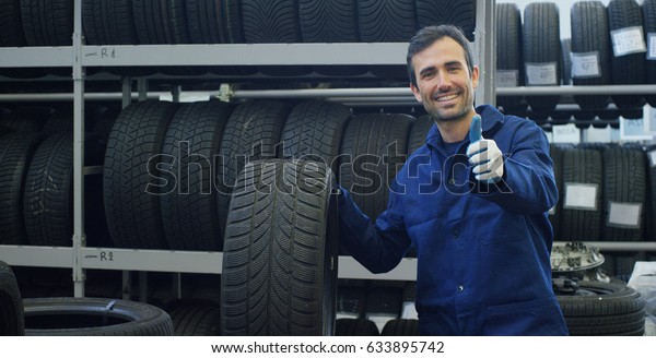 Portrait of a young beautiful car mechanic in a\
car service, in the background of rubber. Concept: repair of\
machines, fault diagnosis, repair specialist, technical maintenance\
and on-board computer.