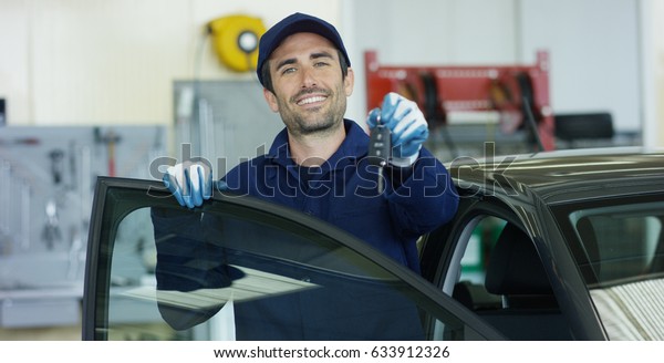 Portrait of a young beautiful car mechanic in a\
car-care center, with keys in his hands. Concept: repair of\
machines, fault diagnosis, repair specialist, technical maintenance\
and on-board computer.