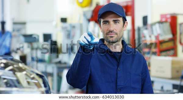 Portrait of a young beautiful car mechanic in a\
car workshop, in the background of service. Concept: repair of\
machines, fault diagnosis, repair specialist, technical maintenance\
and on-board computer