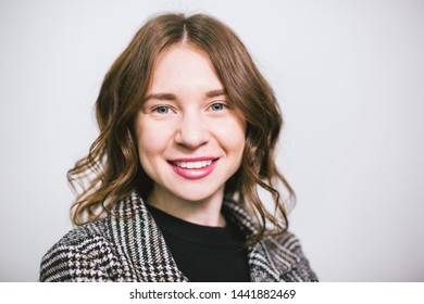 Portrait young beautiful caucasian woman on white background. European girl model posing background of wall in studio. Business woman in jacket and black turtleneck with smile and curly wavy hair.