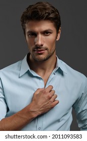 Portrait of young beautiful confident european businessman. Bearded man with dark hair wear blue shirt and looking at camera. Isolated on dark gray background. Studio shoot