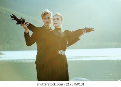 Portrait Of Young Beautiful Couple In Black Elegant Clothes Spending Romantic Time By The Sea At Sunset. Historical Romance Novel. 19th Century.