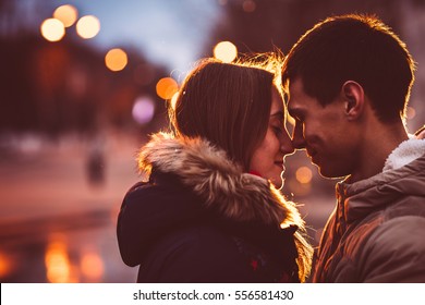 Retrato de jovem casal bonito beijando em um dia chuvoso de outono. Filtrado com grão e luz piscando