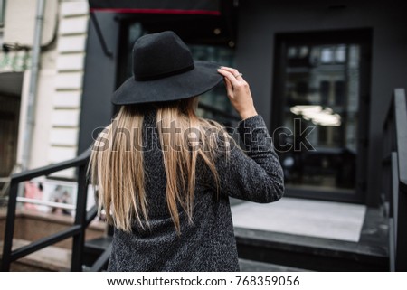 Portrait of a young beautiful fashionable girl wearing sunglasses. Model in a stylish black hat. Harmoniously similar clothes in gray tones. Street style. Women's fashion.