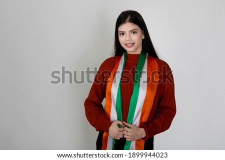 Portrait of a young beautiful female wearing a scarf looking like the Indian flag, tricolour on display by pretty woman to show national pride.