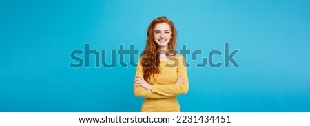 Portrait of young beautiful ginger woman with freckles cheerfuly smiling looking at camera. Isolated on pastel blue background. Copy space