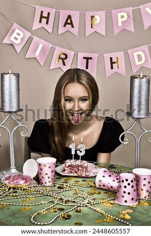 Portrait of young beautiful girl with birthday cake sitting at the table
