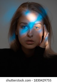 Portrait Of Young Beautiful Girl In Dark Studio With Ray Of Blue Light On Her Face