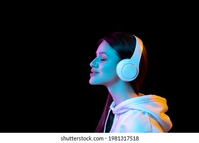 Portrait of young beautiful girl in headphones isolated over dark background. - Shutterstock ID 1981317518