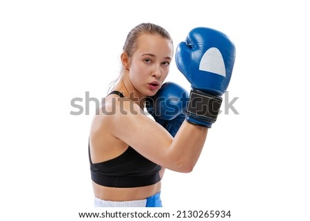 Portrait of young beautiful girl, professional boxer in boxing shorts and gloves posing isolated on white studio background. Sport, competition, show, power, action concept.