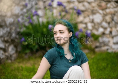 Portrait of a young beautiful girl sitting on the grass in the park