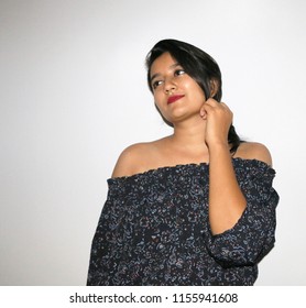 Portrait Of A Young And Beautiful Girl, Stalking Someone With Her Expressive Eyes And Delightful Smile. Studio Shot Of Good-looking Beautiful Girl Isolated Against Blank Studio Wall.