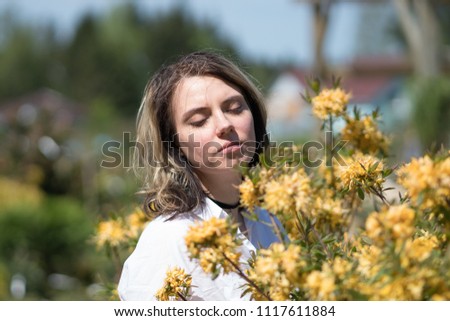 portrait of a young beautiful girl in a summer park with yellow flowers