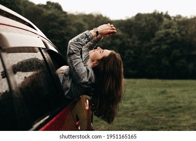 Portrait Of A Young Beautiful Happy Woman In A Denim Jacket Looks Out Of The Car Window In Nature In The Rain. Enjoy The Journey, After Quarantine Coronavirus. Inspiration, Have Fun, Girl, Transport