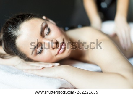 Portrait of a young and beautiful lady being massaged with hot stones on her back