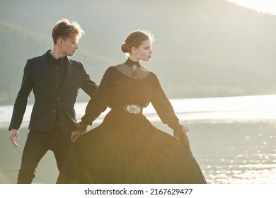 Portrait Of Young Beautiful Romantic Couple In Black Elegant Clothes Standing By The Sea And Dancing Gracefully. Historical Romance Novel. 19th Century.