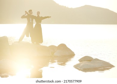 Portrait Of Young Beautiful Romantic Couple In Black Elegant Clothes Standing By The Sea And Dancing Gracefully. Historical Romance Novel. 19th Century.