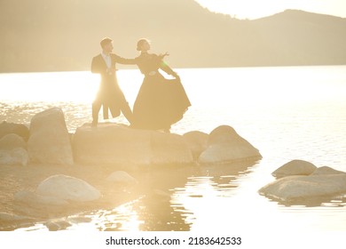 Portrait Of Young Beautiful Romantic Couple In Black Elegant Clothes Standing By The Sea And Dancing Gracefully. Historical Romance Novel. 19th Century.