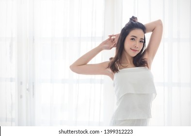 Portrait of young beautiful sexy asian woman relax stretching in bedroom. Smile happy face asian girl look up on white certain. Beauty treatment perfect clear under arm skin makeup spa asia lifestyle 