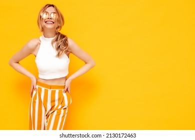 Portrait Of Young Beautiful Smiling Blond Female In Trendy Summer Clothes. Carefree Woman Posing Near Yellow Wall In Studio. Positive Model Having Fun Indoors. Cheerful And Happy