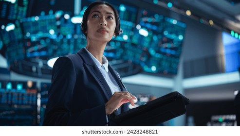 Portrait of a Young Beautiful Stock Exchange Broker Using Tablet Computer, Researching Real-Time Stocks Data, Analyzing Commodities and Exchange Market Charts. Professional Investment Banker in Office - Powered by Shutterstock