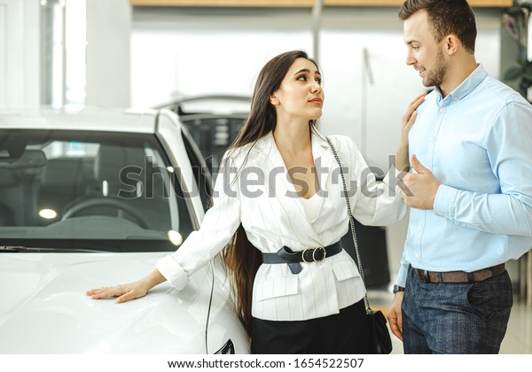 portrait\
of young beautiful woman begging her husband to buy new auto in\
dealership. married couple looking for new\
car