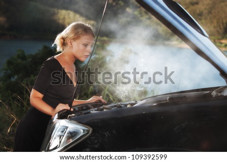 portrait of young beautiful woman with broken car aside