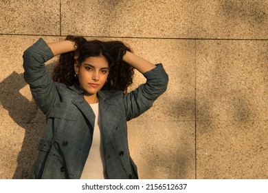 Portrait of young and beautiful woman, brunette, with curly hair, jacket with hands in her hair and seductive look. Concept beauty, fashion, trend, model, seduction.