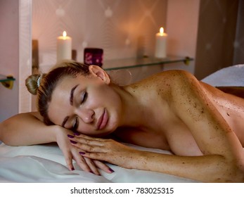 Portrait of young beautiful woman with closed eyes lies at skin care scrub SPA procedure in luxury beauty salon.