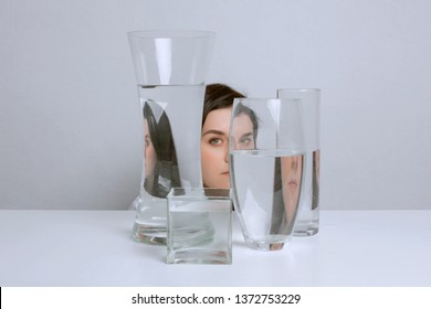 Portrait Of Young Beautiful Woman. Distorted Reflection In Glass Vases With Water.