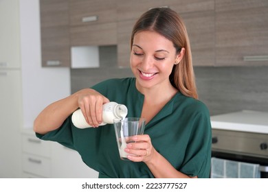 Portrait Of Young Beautiful Woman Fills The Glass With Kefir At Home