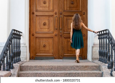 Portrait Of A Young Beautiful Woman In A Green Dress. Against The Background Of An Old Door. Back View