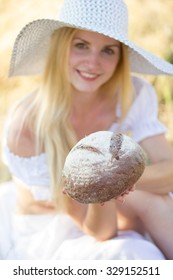 portrait of young beautiful woman holding fresh tasty bread in summer green park. soft focus