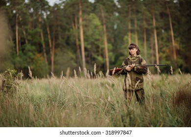 portrait Young beautiful woman hunter with a shotgun in the forest