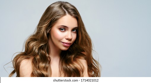 Portrait of young beautiful woman isolated at grey background. Blonde girl with long and shiny wavy hair . Smiling friendly girl with curly hairstyle - Shutterstock ID 1714021012