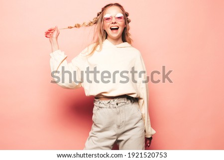 Portrait of young beautiful woman looking at camera.Trendy female smiling in casual summer hipster clothes. Positive and funny model posing near pink wall in studio in sunglasses.Happy and cheerful