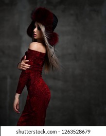 Portrait of young beautiful woman in new red fashion arctic fox winter fur ear flaps hat on dark background