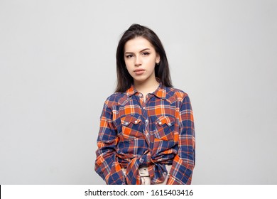 Portrait Young Beautiful Woman Not Smiling In Plaid Shirt Isolated On White-gray Background. Girl With Minimal Natural Make-up On Her Face. The Photo Is Not Retouched With Natural Defects On The Skin.