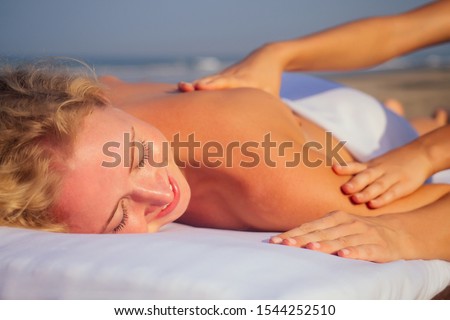 portrait of young beautiful woman on massage table beach morning getting spa on bach and sholders