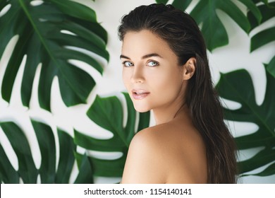 Portrait of young and beautiful woman with perfect smooth skin in tropical leaves. Concept of natural cosmetics and skincare. - Shutterstock ID 1154140141
