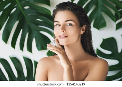 Portrait of young and beautiful woman with perfect smooth skin in tropical leaves. Concept of natural cosmetics and skincare. - Shutterstock ID 1154140219