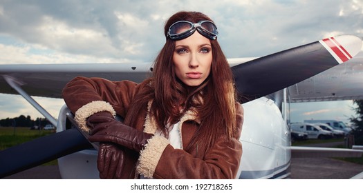 Portrait Of Young Beautiful Woman Pilot In Front Of Airplane. 