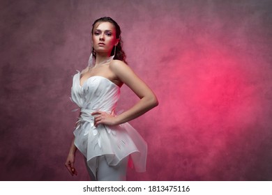 Portrait Of A Young Beautiful Woman In A Smart White Pantsuit, Textured Pink Background. Bride In A Modern Style