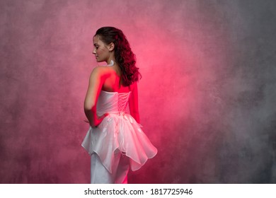 Portrait Of A Young Beautiful Woman In A Smart White Pantsuit, Textured Pink Background. Bride In A Modern Style